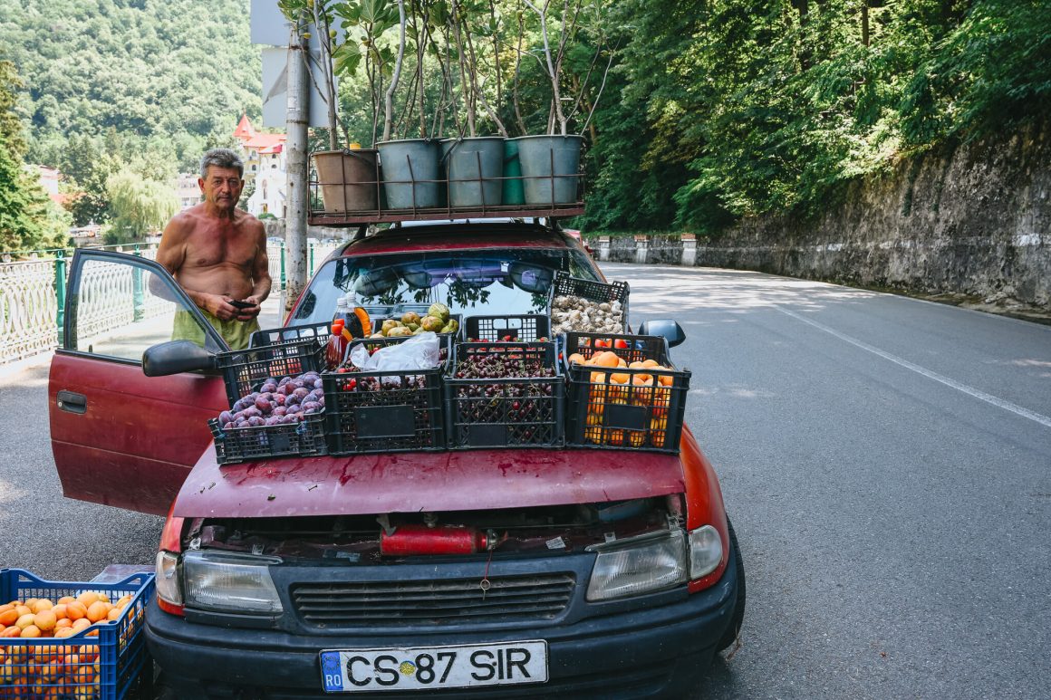 Pan sprzędający warzywa i owoce ze swojego samochodu w Baile Herculane, w Rumunii